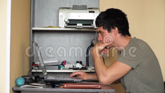 坐在桌子旁的那个人在用笔记本电脑工作因为冠状病毒在隔离期间的远程工作在混乱中视频的预览图
