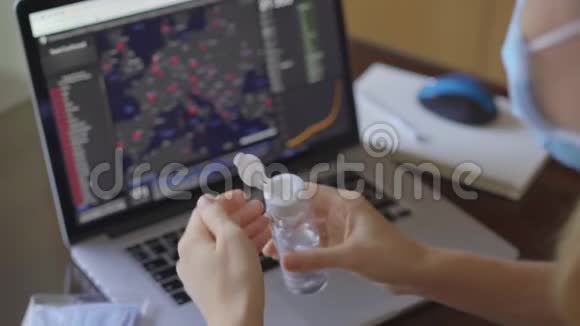 一位年轻女子戴着医用口罩看着电脑屏幕上的感染人数视频的预览图