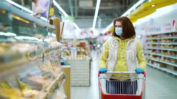 带着医用口罩和手套的家庭主妇在超市买新鲜糕点视频的预览图