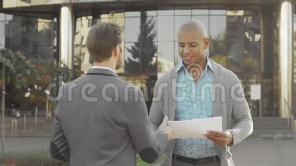 英俊的年轻商人在户外和同事握手视频的预览图