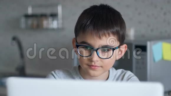 一个正在使用在线技术学习的小学生和一台笔记本电脑坐在家里的桌子上的画像视频的预览图