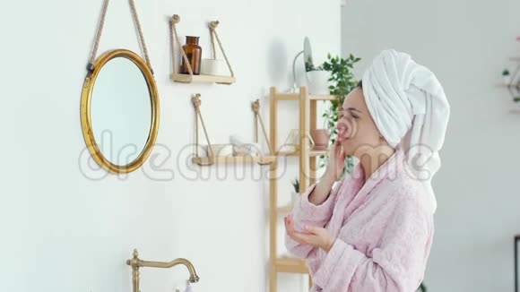女人在浴室的脸上涂上护肤霜视频的预览图