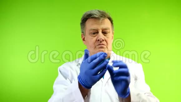 穿着白大褂的严肃的高级成人医生脱下了他的橡胶手套这种手套外界感染的保护绿色视频的预览图