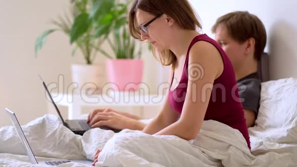 一个男人和女人在卧室里用笔记本电脑工作视频的预览图