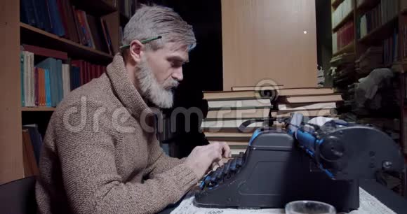 一位留着灰白胡须耳后有支铅笔的老作家正在用打字机视频的预览图