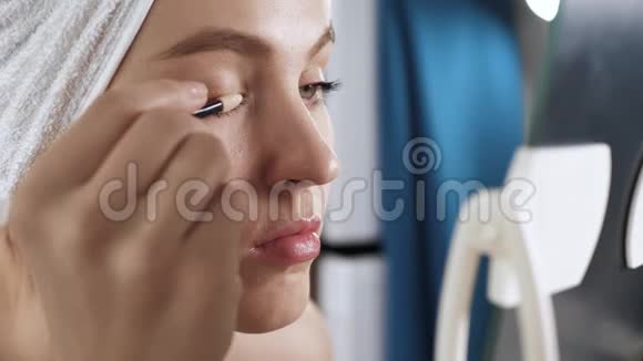 女孩把眼影涂在脸上浴室里的年轻女子右眼上有阴影化妆师化妆师视频的预览图