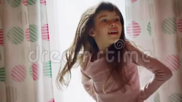 有趣可爱的艺术小女孩的长发在窗户附近唱歌跳舞视频的预览图