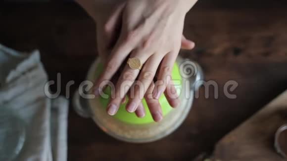 一只雌性手的特写手指上戴着戒指躺在搅拌机的盖子上上面有煮熟的自制鹰嘴豆泥视图视频的预览图
