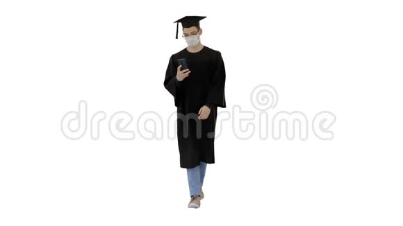 带着毕业礼服的年轻人戴着医疗面具在白色背景下使用智能手机视频的预览图