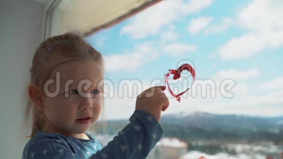 一个小女孩用手指在窗户上画了一颗心视频的预览图