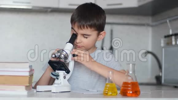 一个男孩用显微镜学习化学并在笔记本上做笔记家庭作业左摄像机移动视频的预览图