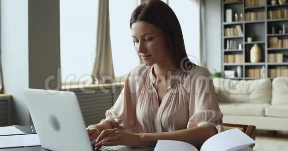 专注的年轻女人坐在桌子旁在电脑上打字视频的预览图
