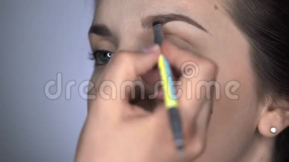 为坐在工作室的漂亮漂亮女人做专业化妆的过程化妆师的眉毛视频的预览图