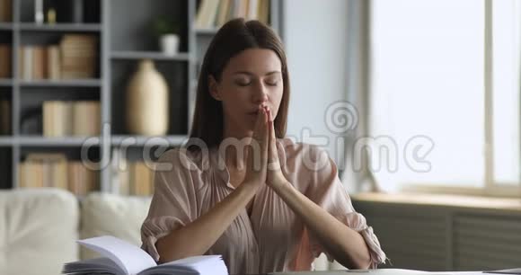 年轻忠诚的女人在家里闭着眼睛祈祷视频的预览图