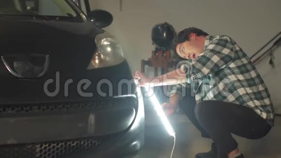 一名机械师用一盏灯检查一辆车并在电话中交谈视频的预览图