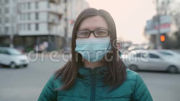 一个戴眼镜和戴医药面具的年轻女孩站在街上4k视频的预览图