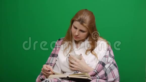 特写镜头生病的女人裹着温暖的毯子喝热茶科维德读书冠状病毒大流行的危险视频的预览图