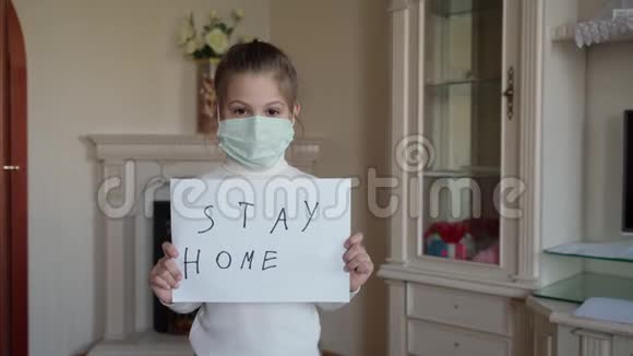 呆在家里的概念戴口罩的小女孩举着牌子说呆在家里保护病毒照顾她们视频的预览图