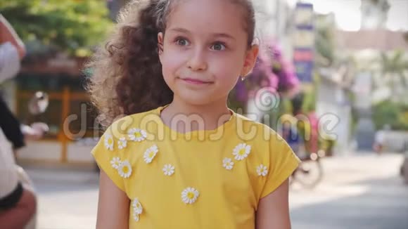 有趣的小女孩微笑着看着街上的摄像机一个可爱的孩子在街上玩耍画着画视频的预览图