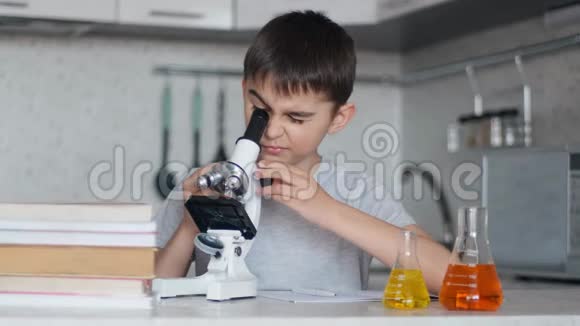 一个男孩用显微镜学习化学并在笔记本上做笔记家庭作业视频的预览图