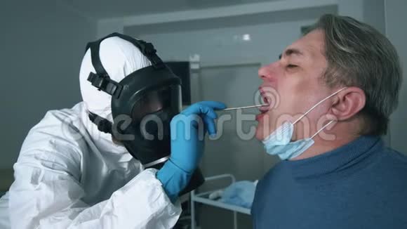 穿防毒服的专家正在检查病人喉咙冠状病毒患者附近保护性医生视频的预览图