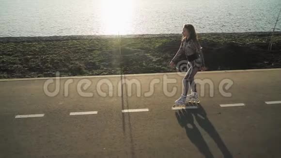 运动苗条的女孩在湖边的小路上滑行美丽的日落慢动作上景对斯泰迪达姆的射击视频的预览图
