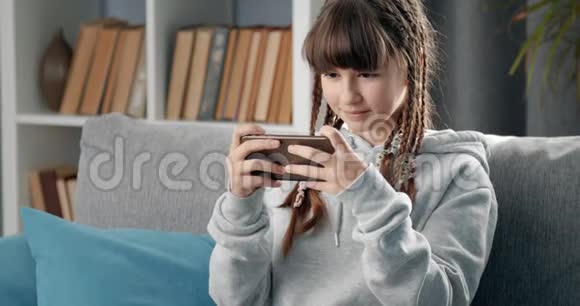 快乐的年轻女孩在玩智能手机游戏视频的预览图