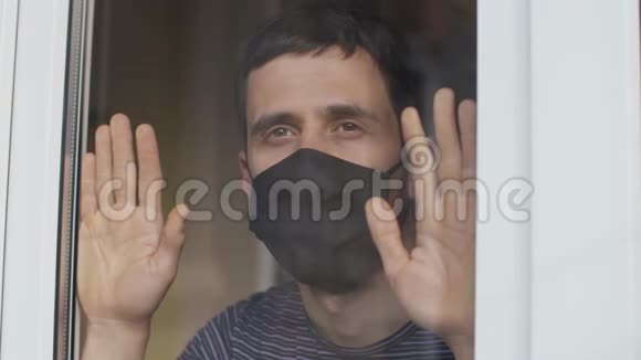 戴防护面罩的人在窗户后面视频的预览图