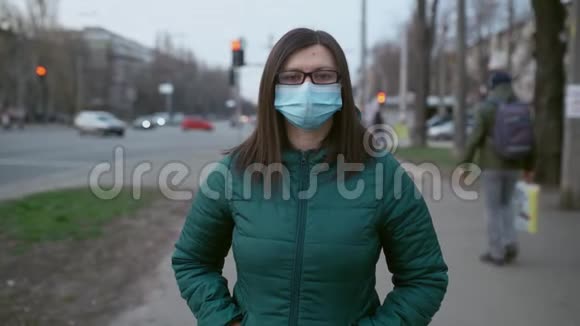 一个戴着眼镜和医用口罩的年轻女孩站在街上视频的预览图