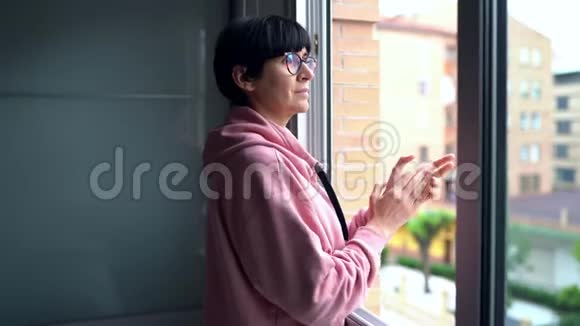 中年妇女在窗户上鼓掌支持那些与冠状病毒作斗争的人视频的预览图