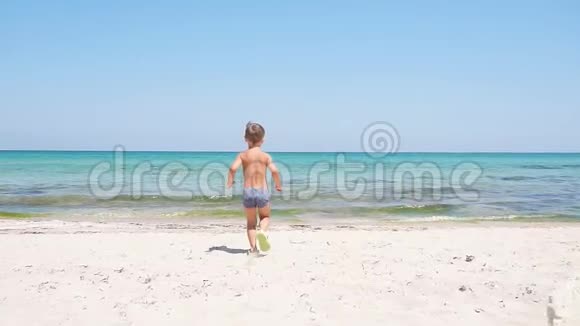 慢动作的小男孩沿着一条岩石小径跑向绿松石的大海视频的预览图