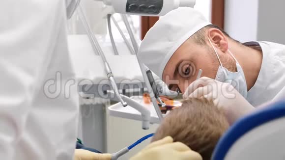 自信的男牙医统一治疗孩子的牙齿近距离拍摄4k红色相机视频的预览图