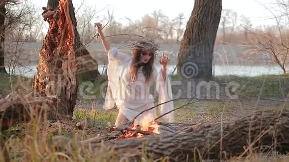 一个女巫的年轻女子坐在树林中的火前视频的预览图