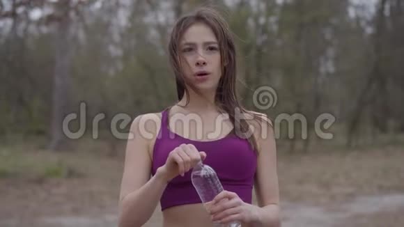 年轻美丽的高加索女人的肖像在户外锻炼时手上有心脏纹身喝水累了视频的预览图