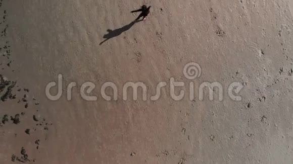 高空俯视图漂亮的体操女子在阳光明媚的沙滩上练习翻车和劈腿穿黑色毛衣和靴子视频的预览图