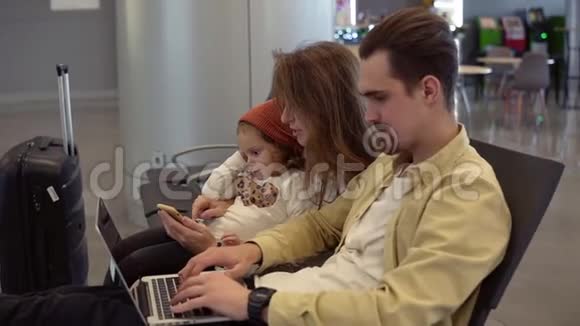 年轻的父亲在机场和家人一起工作等待离开长发母亲招待她视频的预览图