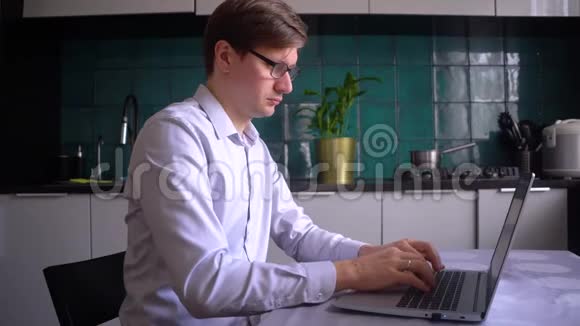 一个男人在家里用笔记本电脑在厨房工作远程工作概念视频的预览图
