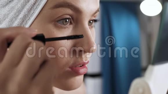 女孩画睫毛年轻迷人的女人在浴室里照镜子用睫毛膏涂睫毛美容师视频的预览图