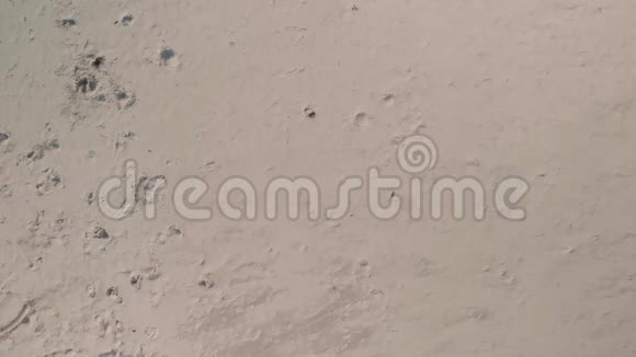 空中景色年轻快乐的女人穿着黑色的毛衣腿在阳光明媚的海滩上躺着做沙子天使视频的预览图