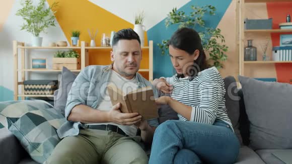 年轻夫妇一男一女读着书在公寓里谈文学视频的预览图