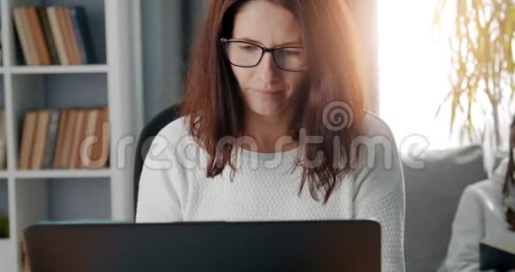 戴眼镜的成年女性使用笔记本电脑远程工作视频的预览图