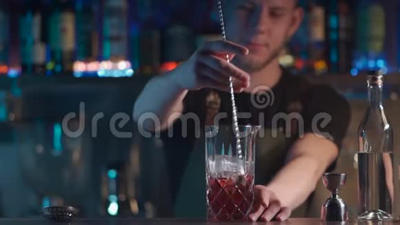 调酒师将经典的negroni鸡尾酒与朗姆酒和冰块混合视频的预览图
