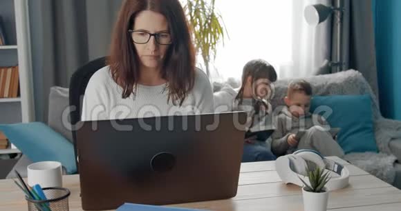 做笔记本电脑工作的成熟女人和她的孩子视频的预览图