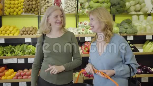 积极的白人成年女性在杂货店谈笑风生金发主妇聊天购物零售视频的预览图