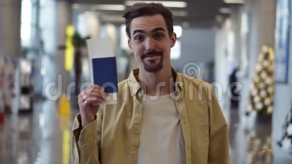 快乐英俊的留胡子的美国男人带着机票挥舞着护照他看着我的眼睛视频的预览图