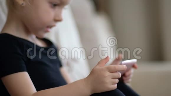 远程学习儿童在线教育在智能手机前在家学习的小女孩儿童观看视频的预览图