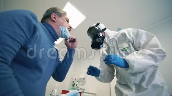 一名男性病人的口腔拭子正被一名护理人员取走冠状病毒患者附近保护性医生视频的预览图