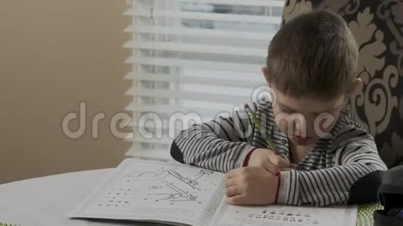 勤奋的小男孩在家学习作业他坐在一张桌子上画画孩子专注于画画视频的预览图