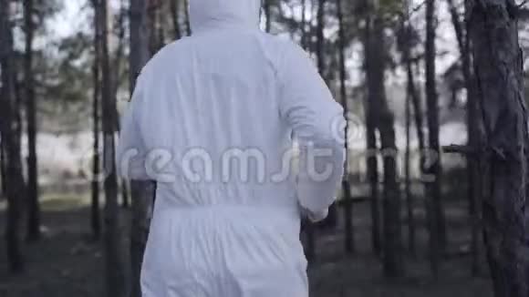 在阳光明媚的春天公园里年轻的白种人身穿白色安全服戴着防护眼镜和面罩视频的预览图