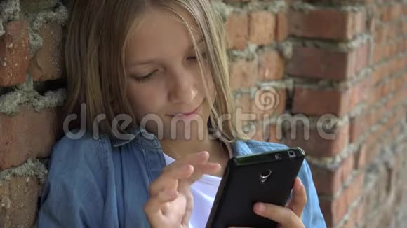 儿童使用智能手机儿童在智能手机上聊天青少年女孩在公园户外浏览互联网视频的预览图
